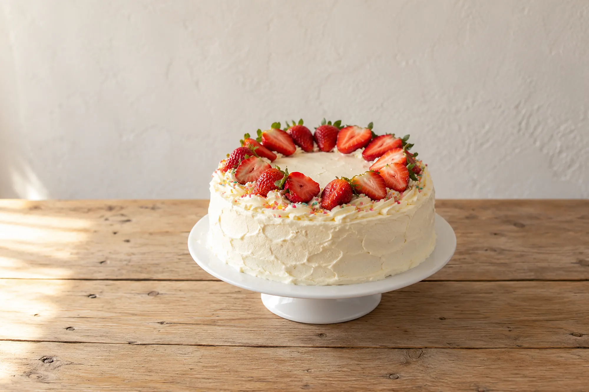 Weiße Sahnetorte mit Erdbeerkranz und bunten Streuseln